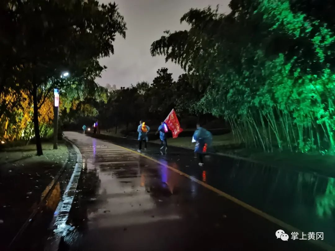 雨后湿润的公园道路上路灯下奔跑的跑者们