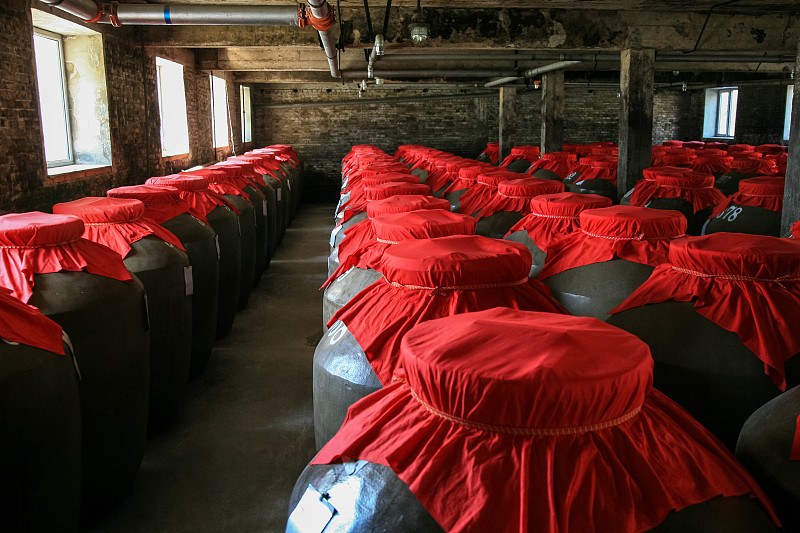 果酒独立站设计案例 醴格「酒窖瓶格」版式封面：老酒窖木架上排列的粗陶酒坛与暖黄灯泡
